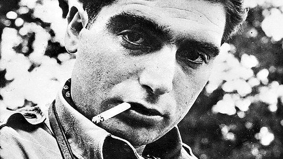 Schwarz-Weiß-Bild von Robert Capa: Ein Mann mit nach hinten gekämmten Haaren und Zigarette im Mund.