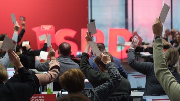 Delegierte halten beim außerordentlichen Landesparteitag der sächsischen SPD Stimmkarten in die Höhe.