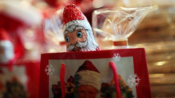 Ein Schokoladen-Weihnachtsmann schaut aus einer Tüte. 