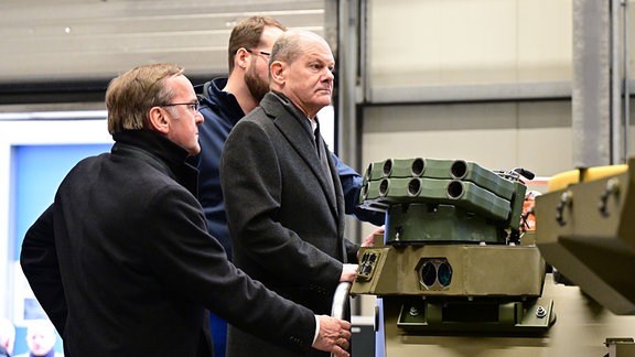 Bundeskanzler Olaf Scholz (2.v.r., SPD), und Boris Pistorius (2.v.l., SPD), Bundesminister für Verteidigung, besichtigen eine Produktionshalle mit Panzerfahrzeugen des Rüstungskonzerns Rheinmetall.