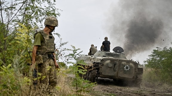 Ein Soldat schaut zurück auf ein gepanzertes Fahrzeug.