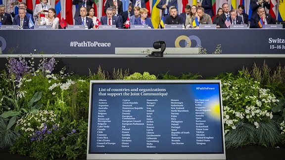 Ein Monitor ist während einer Plenarsitzung bei der Friedenskonferenz zu sehen.