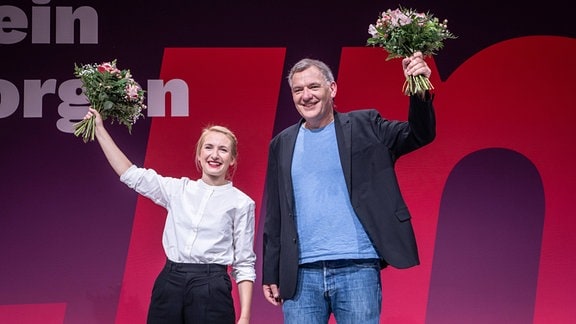 ie beiden Parteivorsitzenden Jan van Aken und Ines Schwedtner schwenken Blumensträuße nach ihrer Wahl auf dem Parteitag