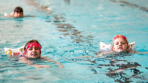 Larissa (l) und Kiara lernen bei der Sommerschwimmschule im Kombibad Gropiusstadt schwimmen. 