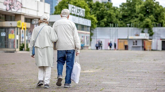 Ein älteres Paar läuft auf dem Gehweg.