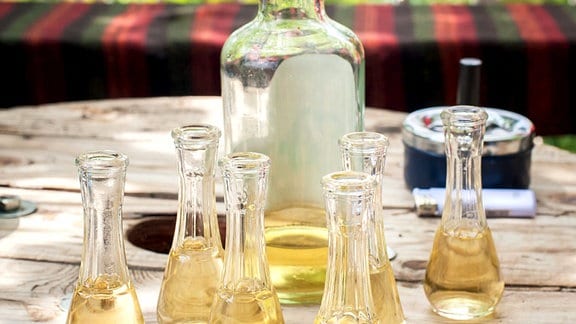 Eine Flasche mit Pflaumenschnaps und gefüllte gläser auf einem tisch.