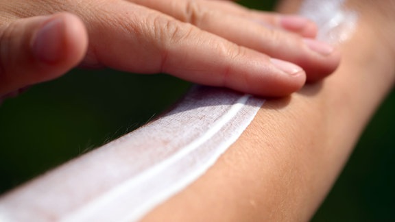 Eine Frau schmiert sich ihren Unterarm mit Sonnencreme ein.