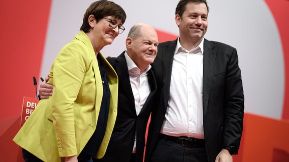 Bundeskanzler Olaf Scholz (M, SPD) nimmt zusammen mit Saskia Esken (l), Vorsitzende der SPD, und Lars Klingbeil, den Applaus entgegen. 