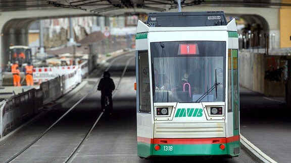 Radfahrer und eine Straßenbahn fahren durch einen Teil der City-Tunnel-Baustelle in Magdeburg, der bereits freigegeben ist.