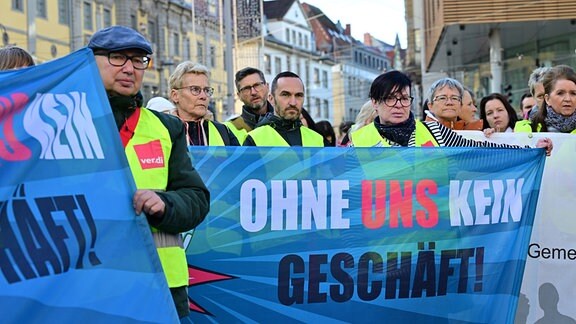 Beschäftigte verschiedener Einzelhandelsunternehmen halten auf einer von der Gewerkschaft verdi organisierten Demonstration in Erfurt Transparente hoch, auf denen "Ohne uns kein Geschäft" steht