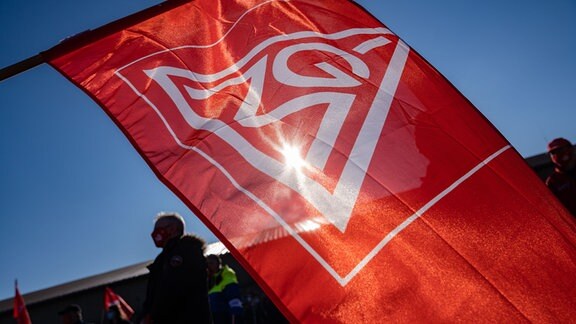 Ein Streikender hält während eines Warnstreiks eine Fahne der IG-Metall Schweinfurt.