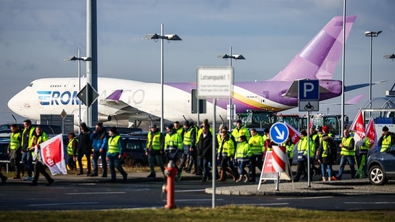 Beschäftigte der Mitteldeutschen Flughafen AG gehen während eines Warnstreiks über den Flughafen Leipzig/Halle.