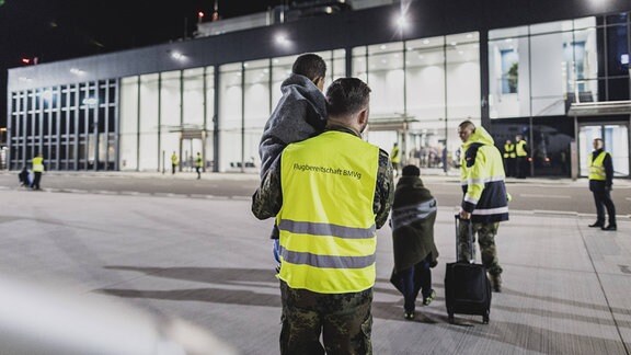 Männer und Kinder des nachts an einem Flughafen