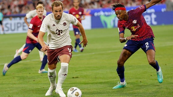 Bayerns Harry Kane (l) kämpft gegen Leipzigs Mohamed Simakan um den Ball. 