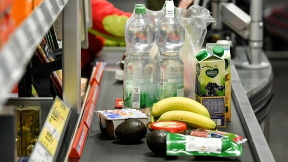 Lebensmittel wie Bananen, Wasser, Saft, Avocados liegen 2019 auf dem Band an einer Kasse im Lebensmittel-Discounter Penny.