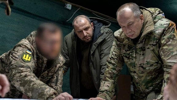 Rustem Umjerow (M), ukrainischer Verteidigungsminister, und Olexander Syrskyj (r), neuer Oberbefehlshaber der ukrainischen Armee, lassen sich in der Ostukraine die Frontlage erläutern.