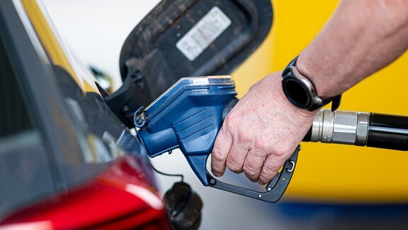 Ein Mann betankt an einer Tankstelle sein Auto.