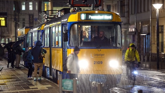 Fahrgäste steigen bei Regen aus und in eine Bahn des Herstellers Tatra auf dem Lindenauer Markt. 