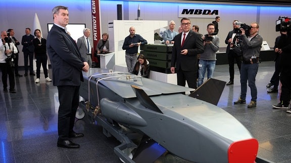 Markus Söder, bayerischer Ministerpräsident (CSU,l), steht mit Joachim Knopf, Geschäftsführer der Taurus Systems GmbH, an einem Ausstellungsstück eines Taurus KEPD 350 Marschflugkörpers im Showroom des Rüstungsunternehmens MBDA.