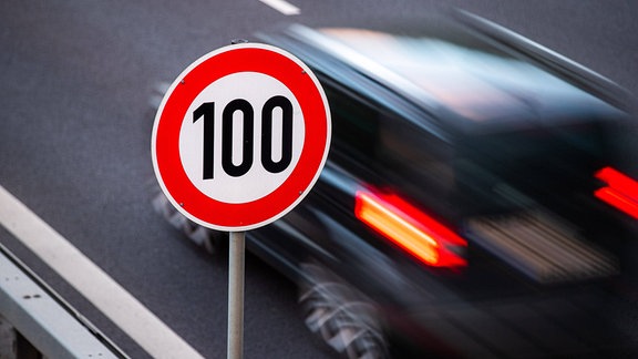 Ein Auto fährt an einem Strassenschild mit der Geschwindigkeitsbegrenzung von 100 km/h vorbei