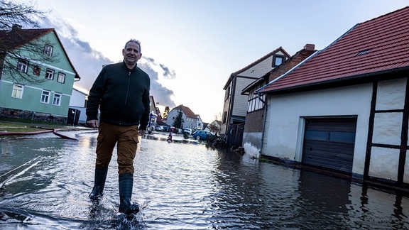 Ein Mann geht über eine überflutete Straße.