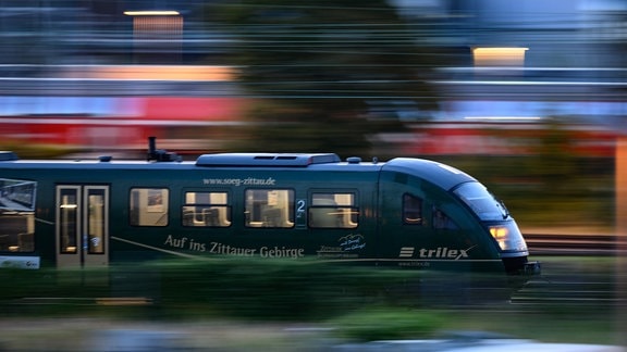 Ein Trilex Zug der Länderbahn fährt am Morgen auf einem Gleis entlang.