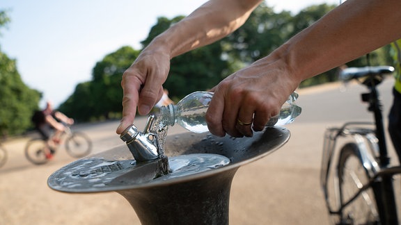 Ein Mann füllt 2022 im Park Kensington Gardens an einem Trinkbrunnen seine Wasserflasche auf.