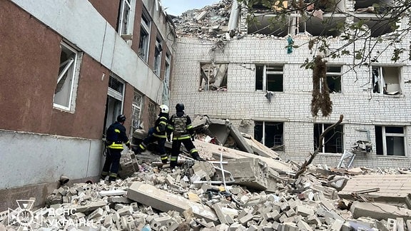 Rettungskräfte inspizieren ein zerstörtes Haus