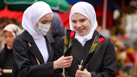 Zwei verschleierte Frauen jeweils mit Blumen