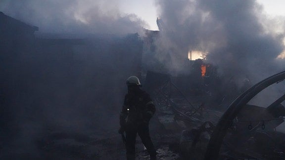 Feuerwehrleute versuchen, das Feuer nach einem Treffer durch russischen Granatenbeschuss in Charkow, Ukraine, zu löschen.