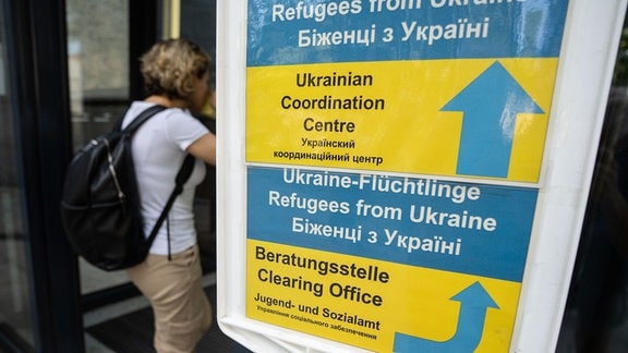 Besucher gehen an einem Hinweisschild der Initiative Ukrainian Coordination Center (UCC) am Eingang zum Amt für multikulturelle Angelegenheiten vorbei. 
