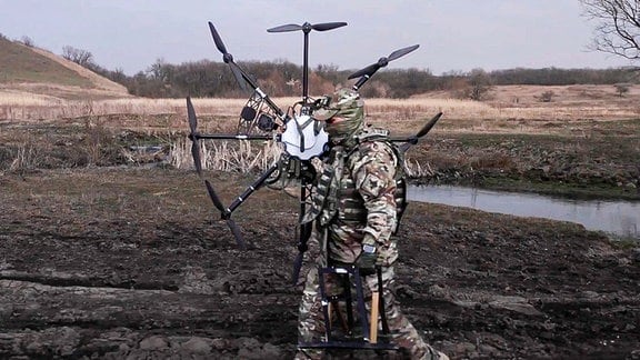 Ein russischer Soldat trägt eine erbeutete ukrainische Drohne, die vom Militär an einem ungenannten Ort in der Ukraine wiederhergestellt und modernisiert wurde.