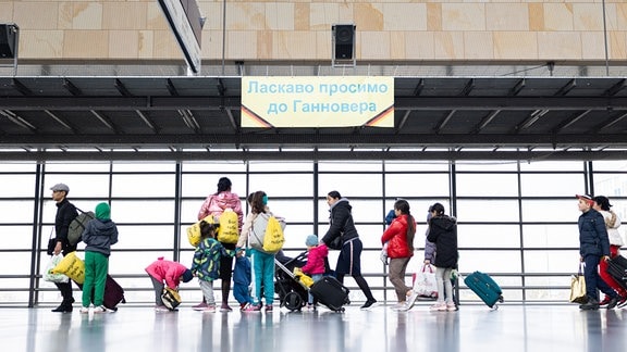 Geflüchtete aus der Ukraine gehen durch die Eingangshalle vom Messebahnhof Laatzen