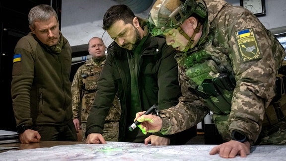 Wolodymyr Selenskyj (M), Präsident der Ukraine, Olexander Syrskyj (r), Kommandeur der ukrainischen Bodentruppen, und Roman Maschowez, stellvertretender Leiter des Präsidialamtes, betrachten eine Landkarte während ihres Besuchs in der Frontstadt in der Region Charkiw. 