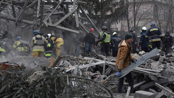 Menschen räumen die Trümmer am Ort eines russischen Luftangriffs.