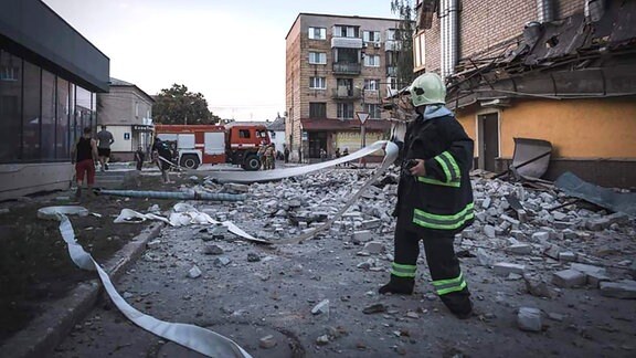 Rettungskräfte an einem Gebäude, das nach Raketenangriffen beschädigt wurde. 