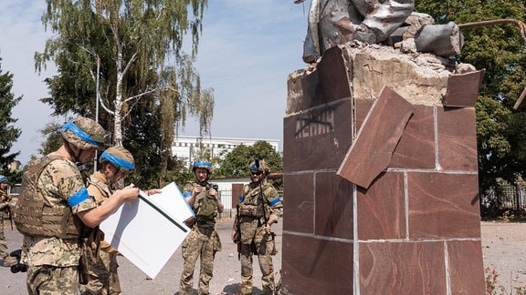 Ukrainische Soldaten vor einem zerstörten Denkmal in der russischen Region Kursk