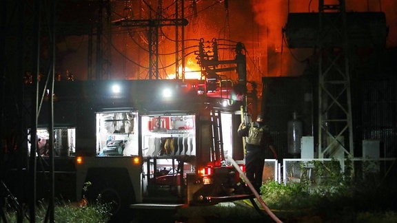 Feuer in einem Elektrizitätswerk, im Vordergrund ein Feuerwehrfahrzeug