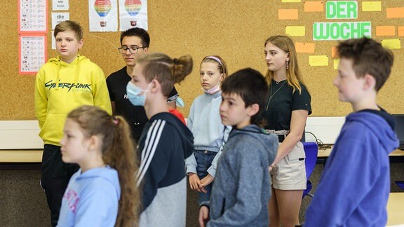 Aus der Ukraine geflüchtete Schülerinnen und Schüler stehen beim Deutschunterricht in einem Gymnasium.