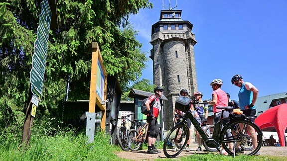 Radler stehen vor dem Turm auf dem 1018 Meter hohen Auersberg im Erzgebirge.