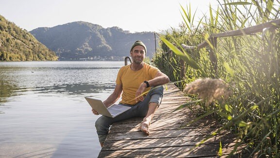 Ein Mann mit Laptop am See.