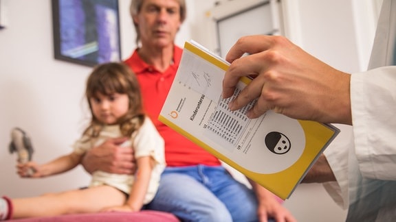 Ein Vater mit Tochter beim Kinderarzt.