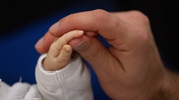 Ein Vater berührt während eines Infant Handling Kurses die Hand seines Kindes.