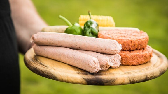 Ein Mann haelt am 09.05.2021 in Wittenberge ein Holzbrett mit verschiedenen Fleischersatzprodukten (gestellte Szene).