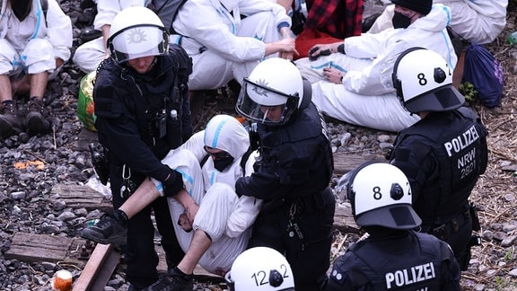 Ein Klimaschutzaktivist der Gruppe «Ende Gelände», der Schienen der Zufahrt zu dem Kohlekraftwerk Scholven in Gelsenkirchen blockiert hatte, wird von Polizisten weggetragen.
