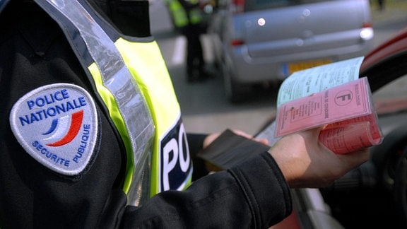 Ein französischer Polizist prüft während einer Verkehrskontrolle in Niort den Führerschein eine Autofahres.