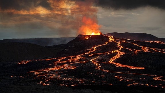 Lava und rötlich erleuchtete Rauchwolk steigen aus dem Vulkan Fagradalsfjallauf Island empor