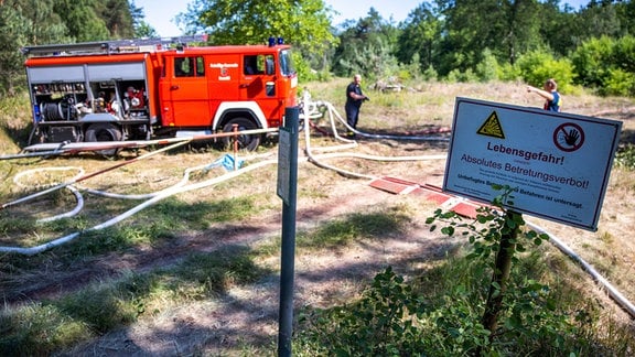 Feuerwehrleute sichern die Löschwasserversorgung bei der Bekämpfung eines Waldbrandes 