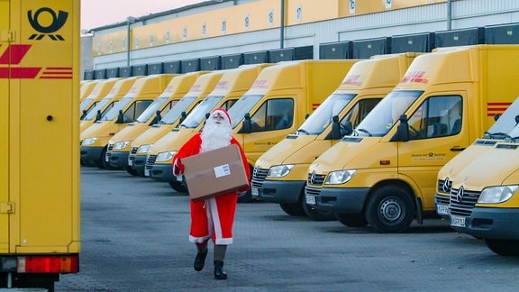 Ein als Weihnachtsmann verkleideter Postbote läuft 2003 mit einem Paket zu seinem Zusteller-Fahrzeug