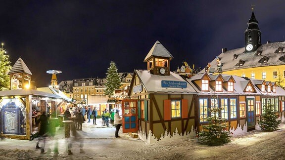 Besucher gehen am 04.12.2017 auf dem leicht verschneiten festlich beleuchteten Weihnachtsmarkt in Annaberg-Buchholz. 